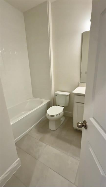 A bathroom features a white bathtub, a toilet, and a vanity with a mirror — 14729 ERICE AVENUE, CLERMONT, FL