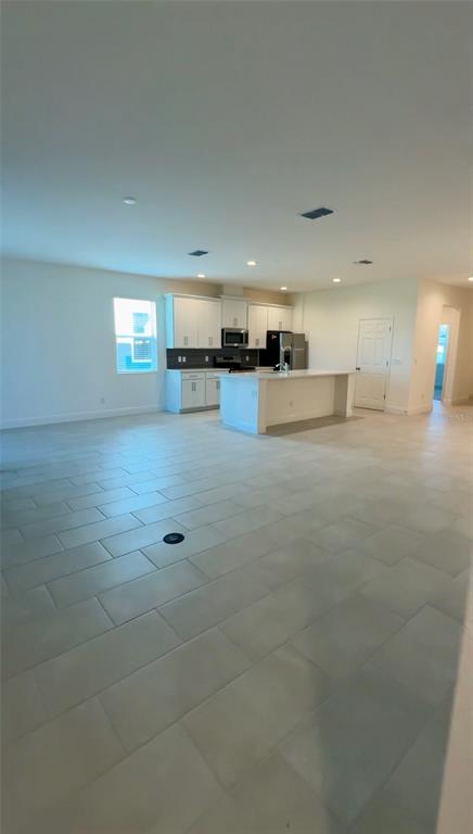 A spacious, open-concept kitchen features white cabinetry, a central island, and light-colored tile flooring — 14729 ERICE AVENUE, CLERMONT, FL