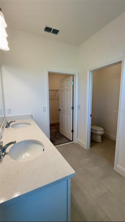 A bathroom features a double vanity with white countertops, a walk-in closet, and a toilet room — 14729 ERICE AVENUE, CLERMONT, FL