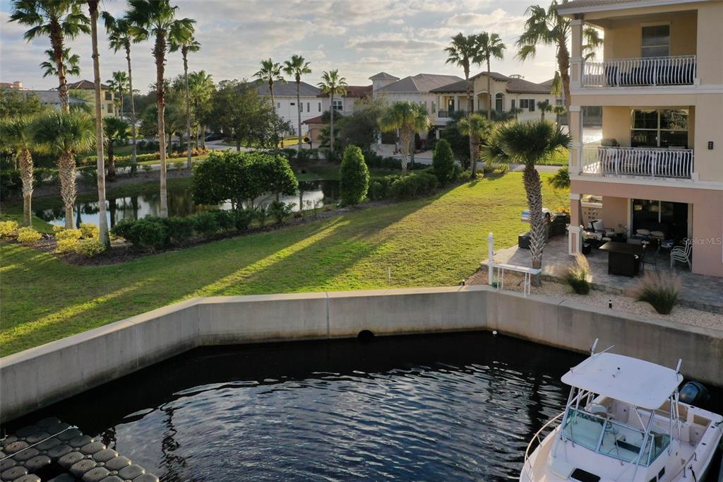 A boat is docked in a canal next to a grassy yard and a multi-story building — 297 YACHT HARBOR DRIVE, PALM COAST, FL