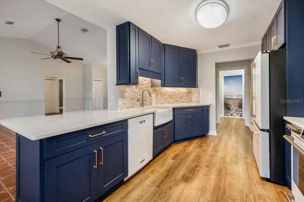 A kitchen features navy blue cabinets, white countertops, a farmhouse sink, and wood-look flooring — 86 FELLOWSHIP DRIVE, PALM COAST, FL