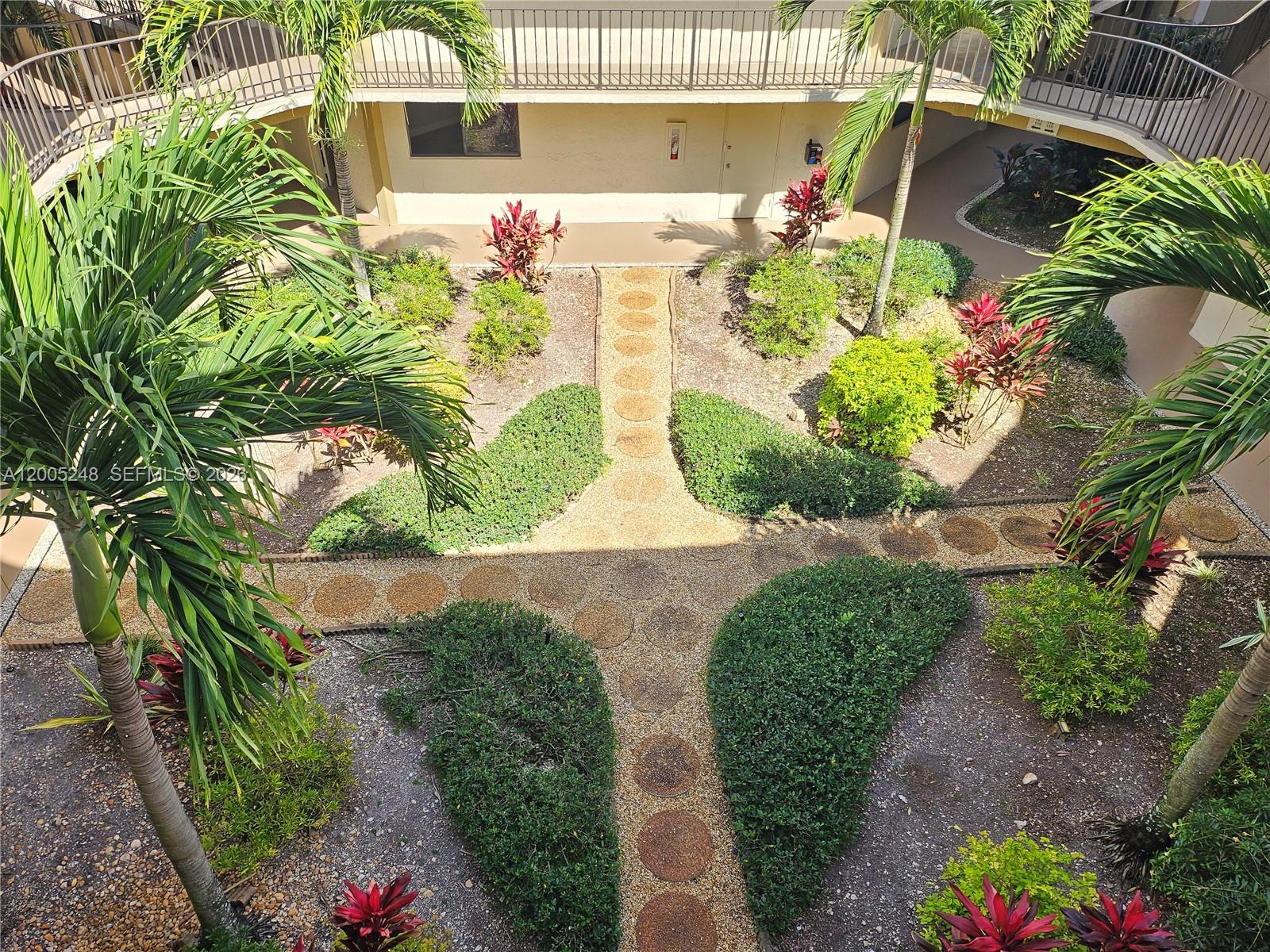 An elevated view of a landscaped courtyard with palm trees and a stone pathway — 8005 SW 107th Ave # 305, Miami FL 33173, MIAMI, FL
