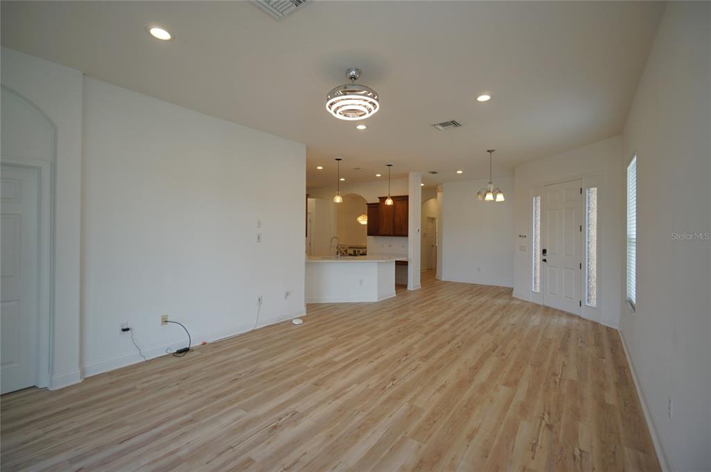 An open-concept living area features light wood-look flooring, recessed lighting, and a kitchen with white counters — 20638 AMANDA OAK COURT, LAND O LAKES, FL