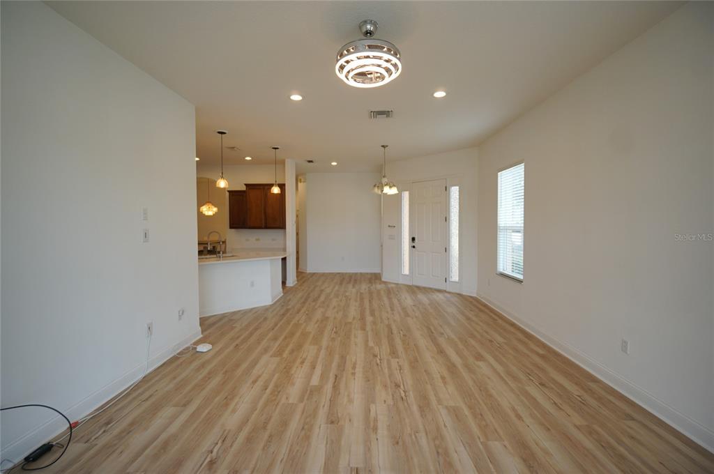 An open-concept living area features light wood-look flooring, white walls, and a kitchen with cabinets — 20638 AMANDA OAK COURT, LAND O LAKES, FL