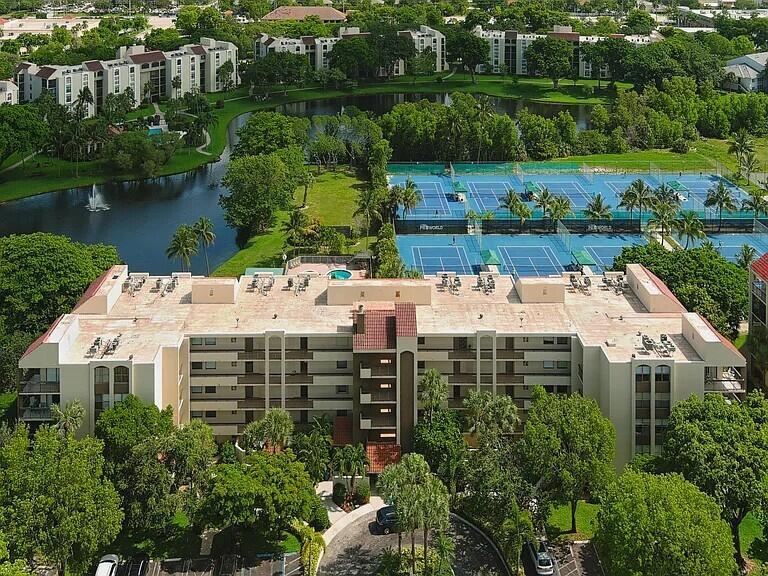 An aerial view shows a multi-story apartment building next to a lake and tennis courts — 955 Egret Circle # 211, Delray Beach FL 33444, DELRAY BEACH, FL