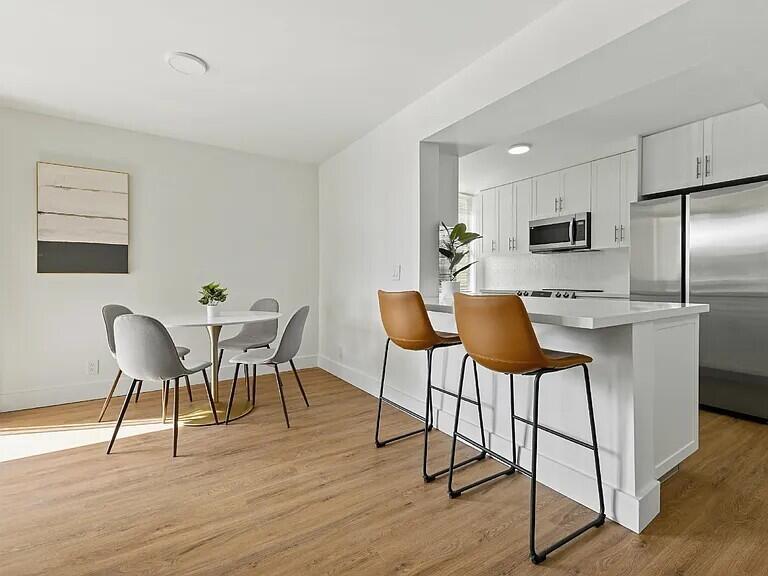 A kitchen with white cabinets and a breakfast bar opens into a dining area — 955 Egret Circle # 211, Delray Beach FL 33444, DELRAY BEACH, FL