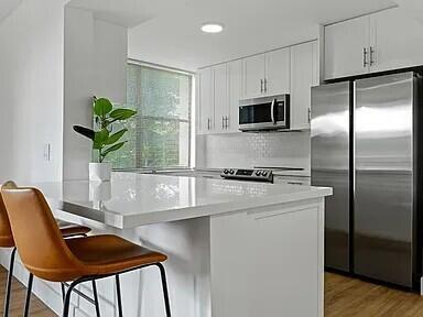 A modern kitchen features white cabinetry, stainless steel appliances, and a white quartz island countertop — 955 Egret Circle # 211, Delray Beach FL 33444, DELRAY BEACH, FL