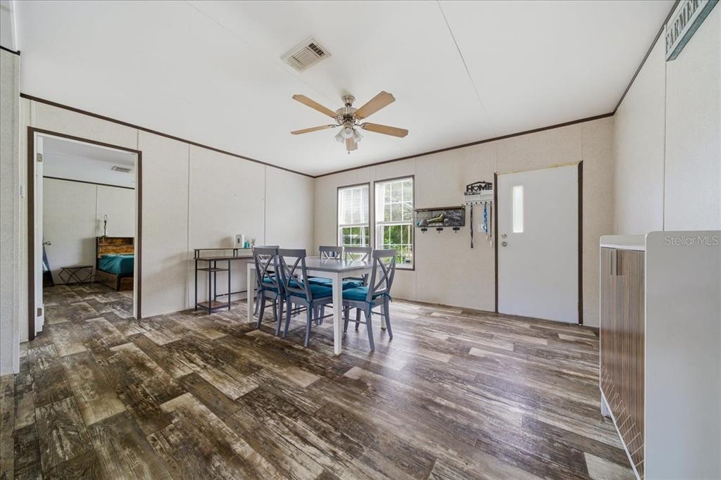 A dining area features wood-look flooring, a ceiling fan, and a view into a bedroom — 444 KORBUS ROAD, BROOKSVILLE, FL