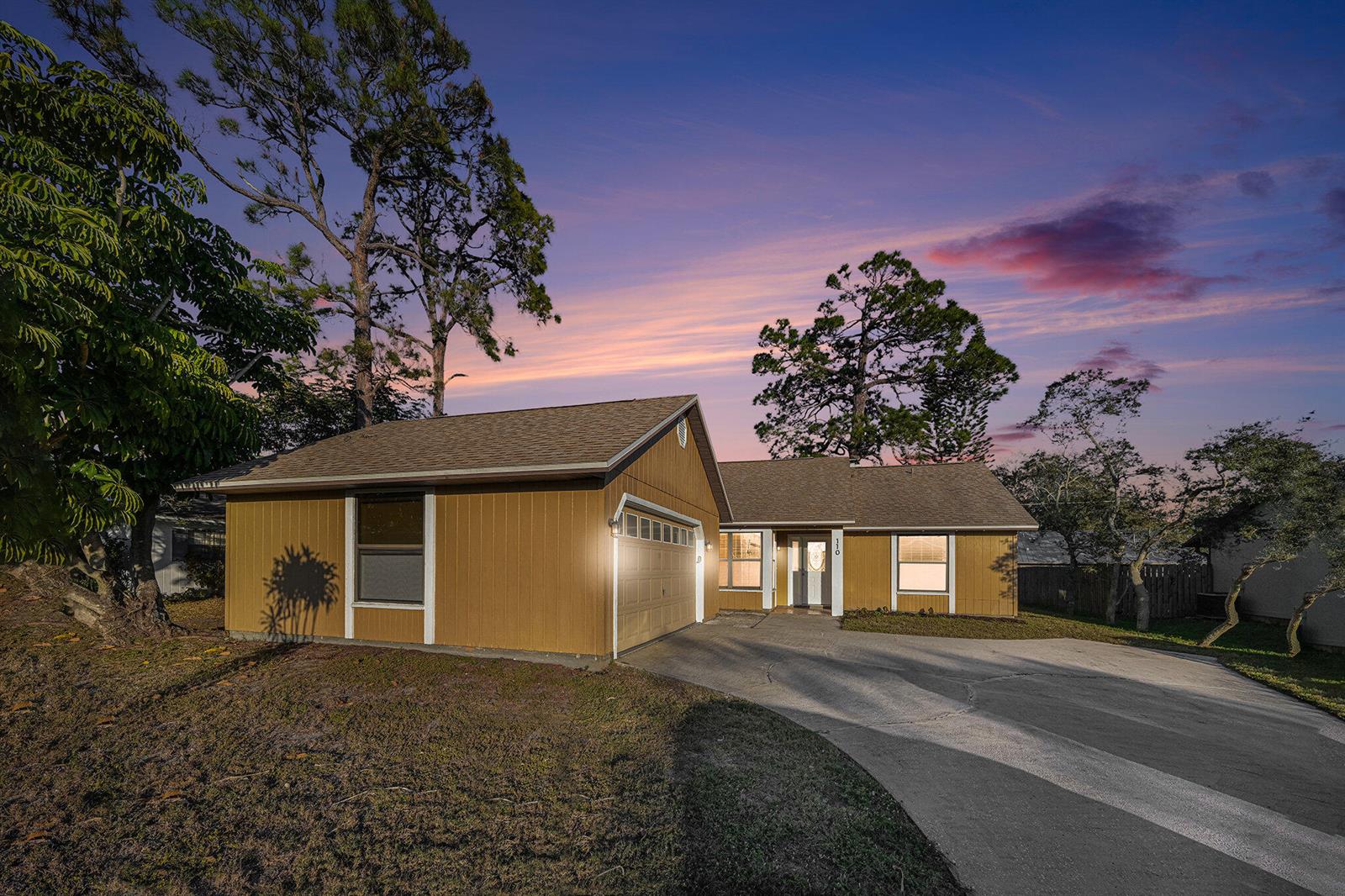 A single-story house with tan vertical siding, a front-facing garage, and a concrete driveway — 110 Cardinal Drive, Sebastian FL 32958, SEBASTIAN, FL