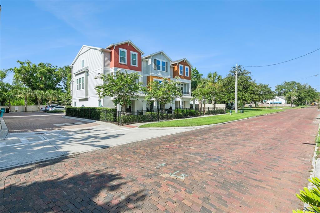 A three-story multi-unit residential building sits beside a brick street and a parking area — 1012 E MARKS STREET, ORLANDO, FL