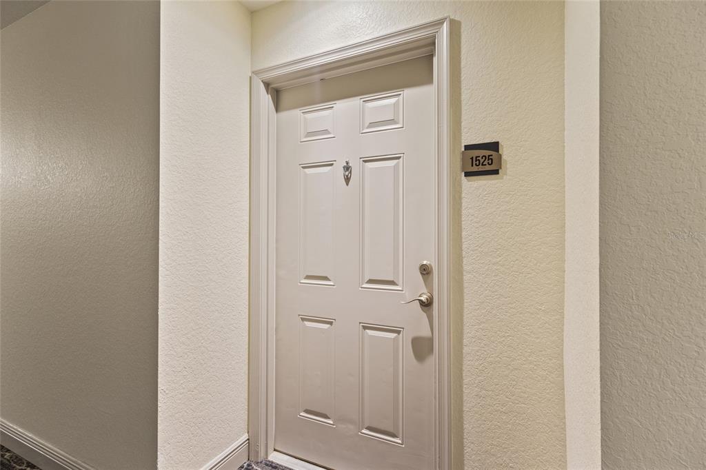 A white front door with a silver handle and a unit number sign on the wall — 1064 N TAMIAMI TRAIL UNIT 1525, SARASOTA, FL