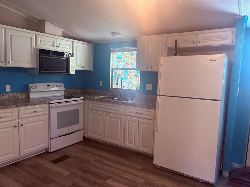 A kitchen features white cabinets, a white stove, a white refrigerator, and blue walls — 7810 W TWIN CANAL LANE, HOMOSASSA, FL