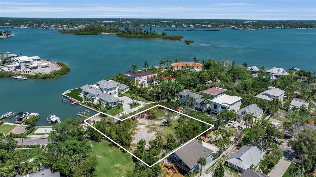 An aerial view shows a vacant, tree-covered waterfront lot outlined in white near residential homes — 0 ROBERTS POINT ROAD, SARASOTA, FL