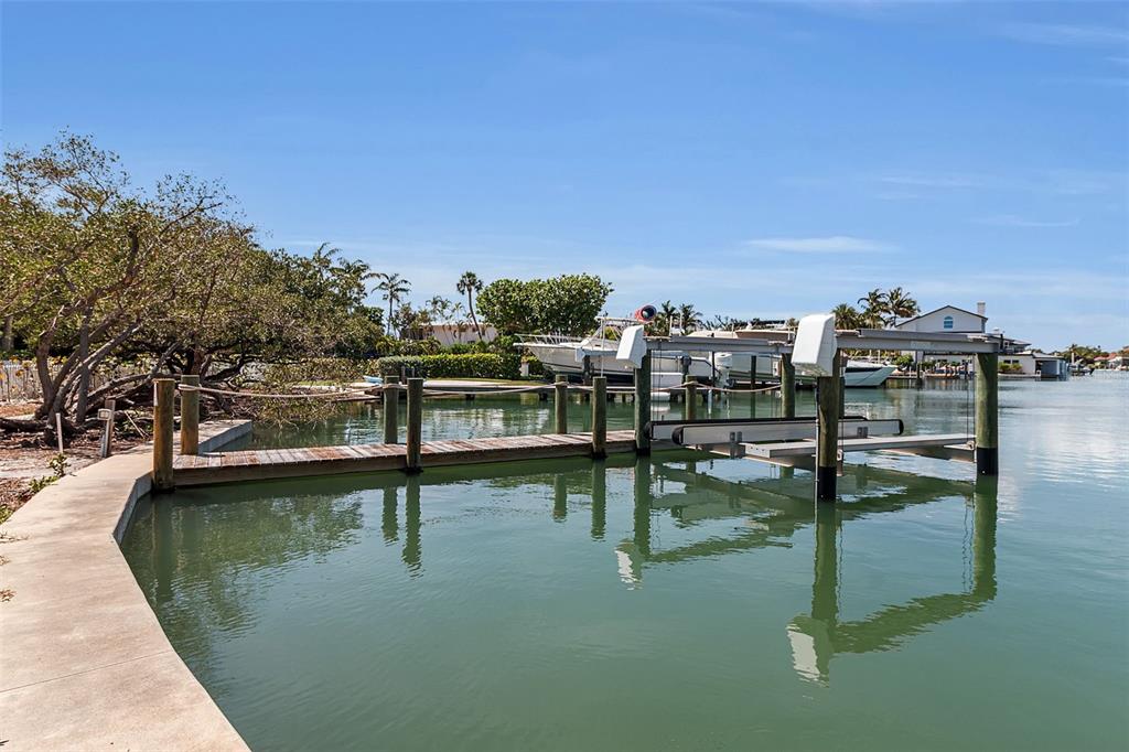 A wooden boat dock with a mechanical lift extends into a calm canal — 0 ROBERTS POINT ROAD, SARASOTA, FL