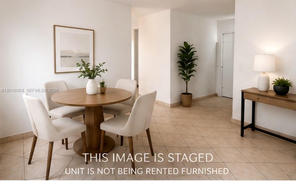 This staged dining area features a round wooden table, four chairs, and tiled flooring — MIAMI BEACH, FL