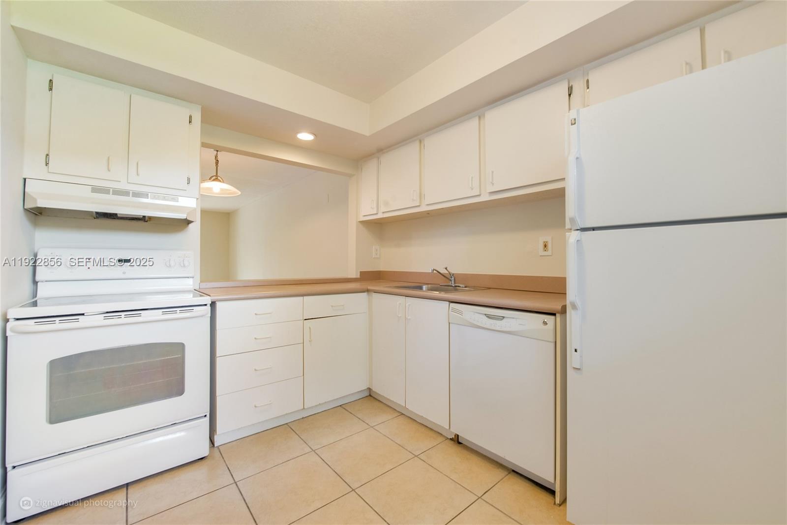 A kitchen features white cabinets, white appliances, tan countertops, and light-colored tile flooring — 4600 SW 67th Ave # 125, Miami FL 33155, MIAMI, FL