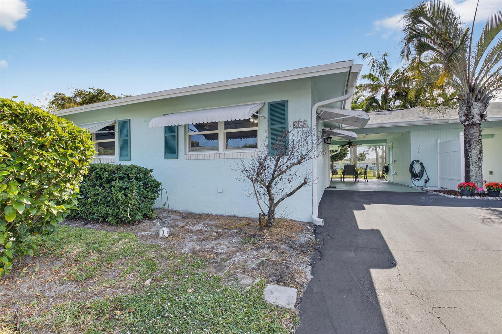 A light blue single-story house features a driveway, a carport, and a small front yard — 634 Hummingbird Lane, Delray Beach FL 33445, DELRAY BEACH, FL