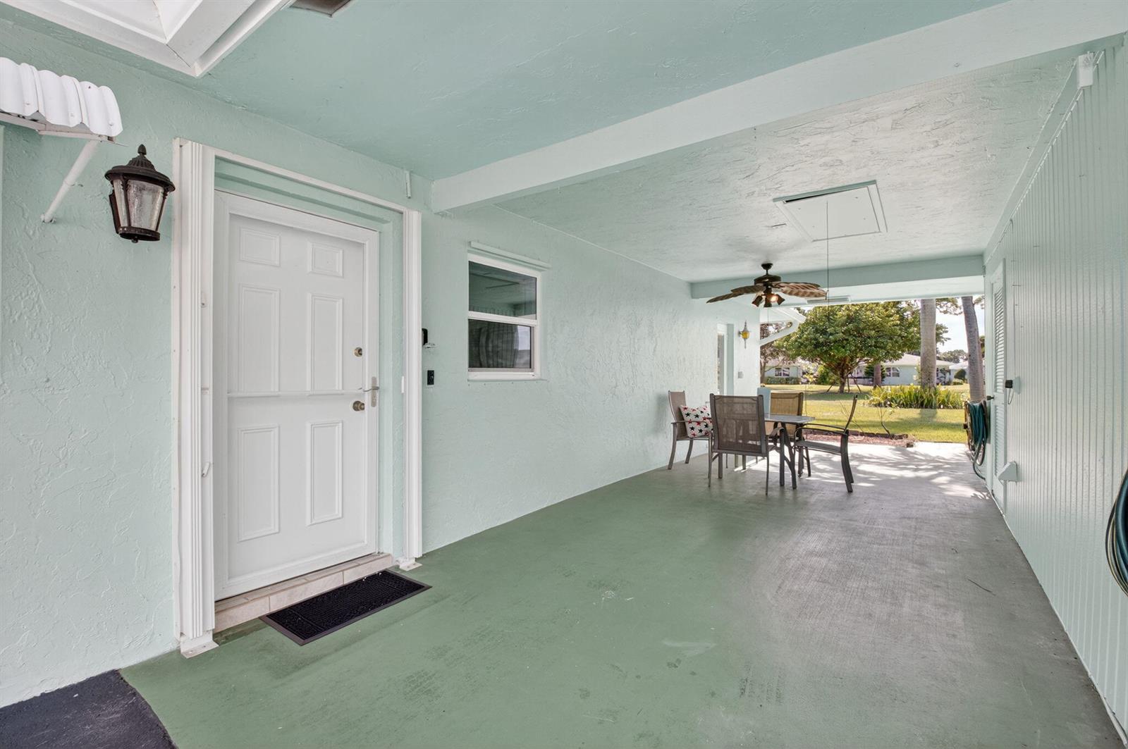 A covered patio with light green walls, a painted floor, and a ceiling fan — 634 Hummingbird Lane, Delray Beach FL 33445, DELRAY BEACH, FL