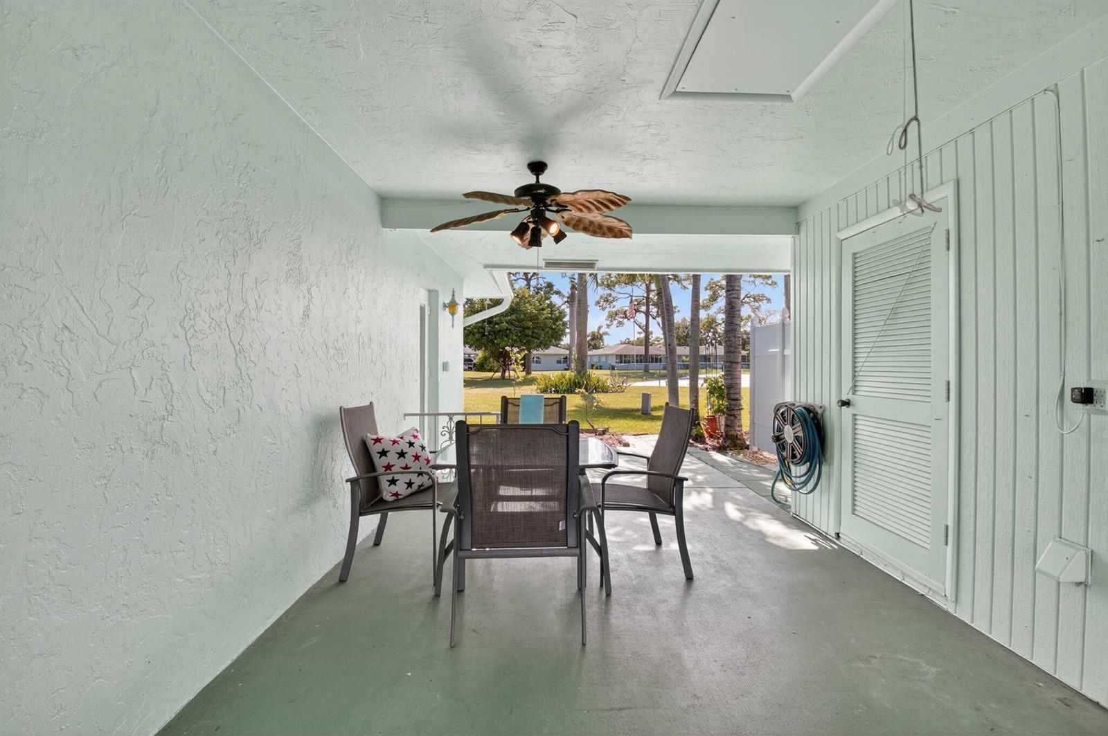 A covered patio features a dining set, a ceiling fan, and a view of the yard — 634 Hummingbird Lane, Delray Beach FL 33445, DELRAY BEACH, FL