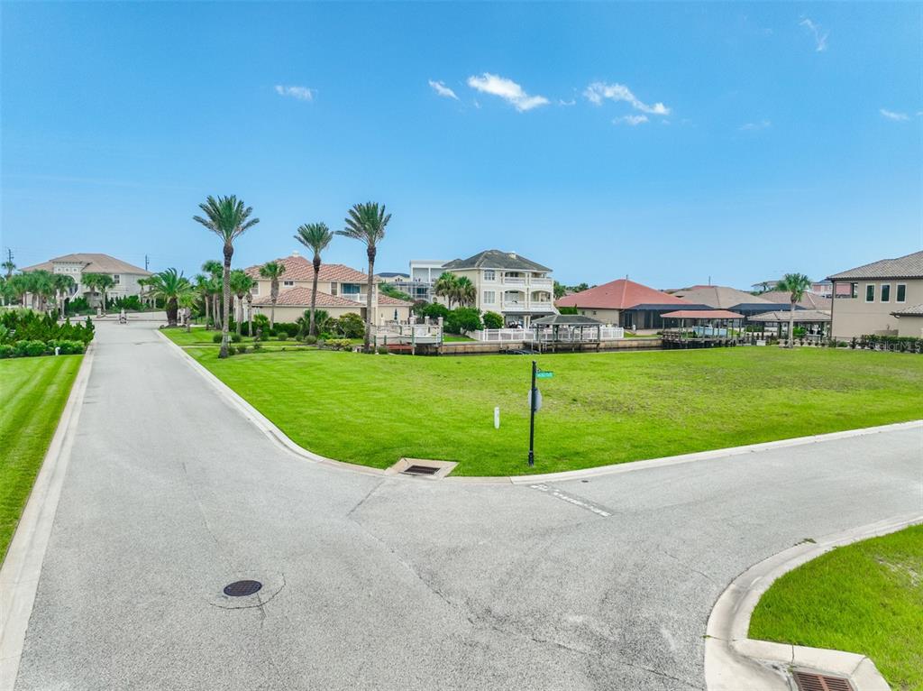 A vacant grassy corner lot sits at a residential street intersection near a canal — 60 MALIBU COVE, FLAGLER BEACH, FL