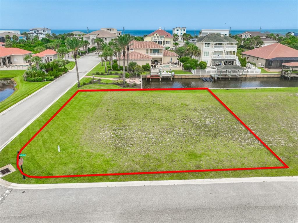 An aerial view shows a vacant, rectangular waterfront lot outlined in red — 60 MALIBU COVE, FLAGLER BEACH, FL