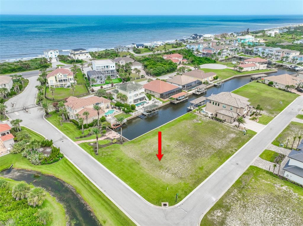 An aerial view shows a vacant waterfront lot situated between two houses in a coastal neighborhood — 60 MALIBU COVE, FLAGLER BEACH, FL