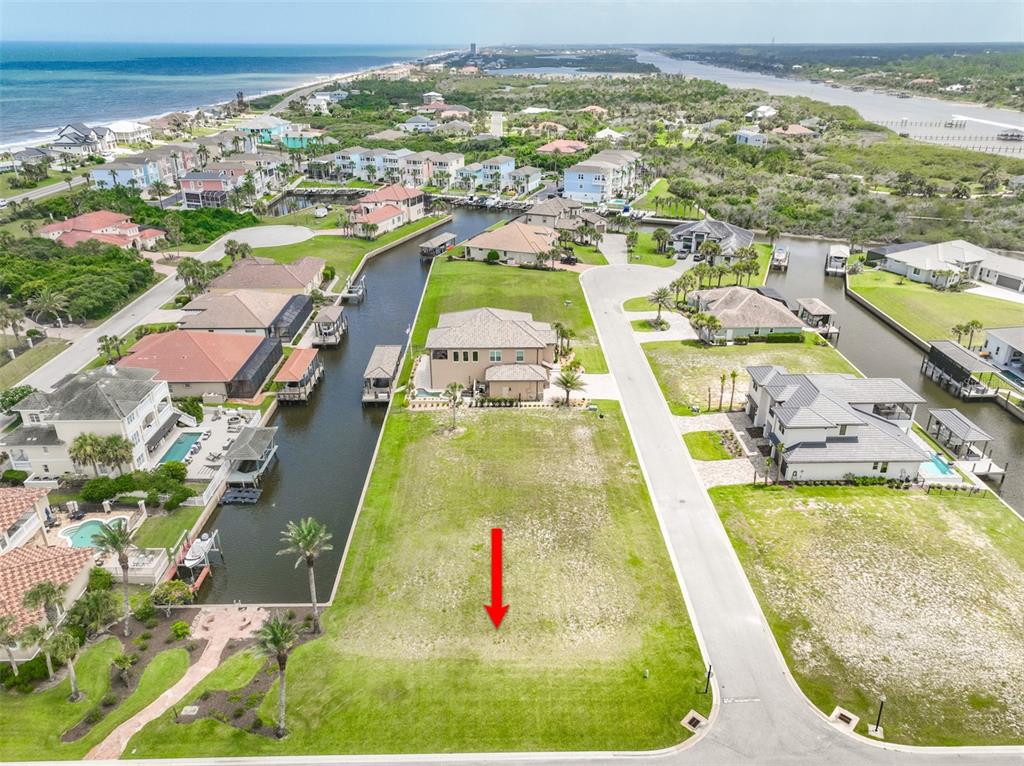 An aerial view shows a vacant waterfront residential lot with a red arrow pointing down — 60 MALIBU COVE, FLAGLER BEACH, FL