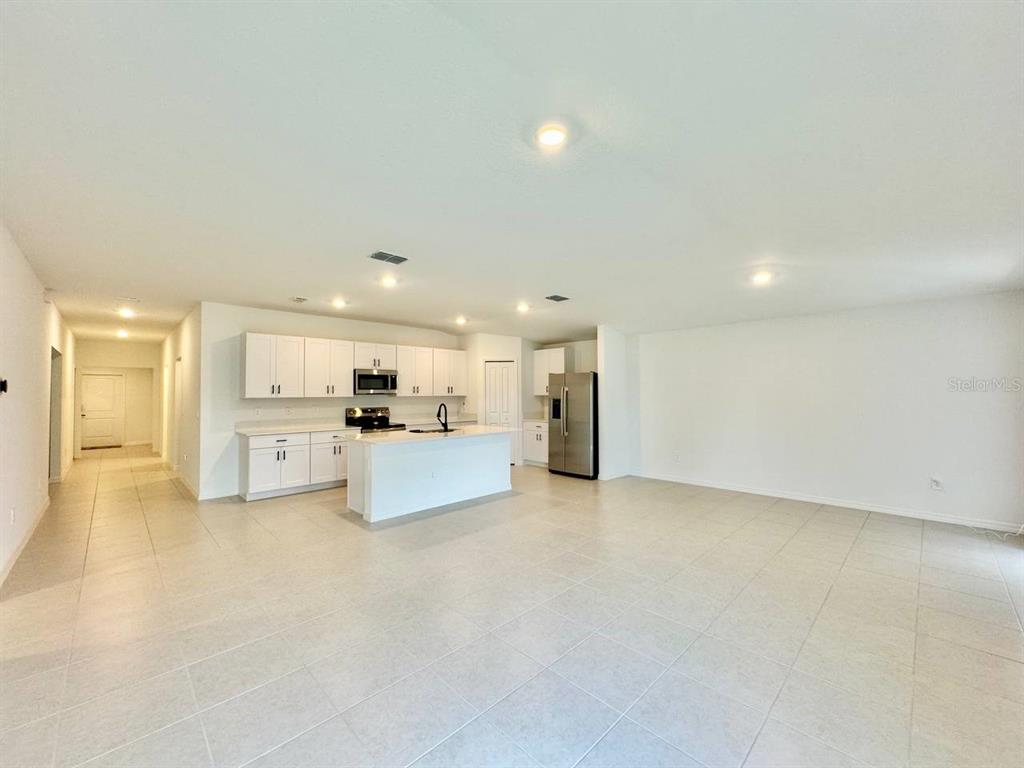 An open-concept kitchen features white cabinetry, stainless steel appliances, and a central island — 10275 PURPLE LEAF COURT, RIVERVIEW, FL