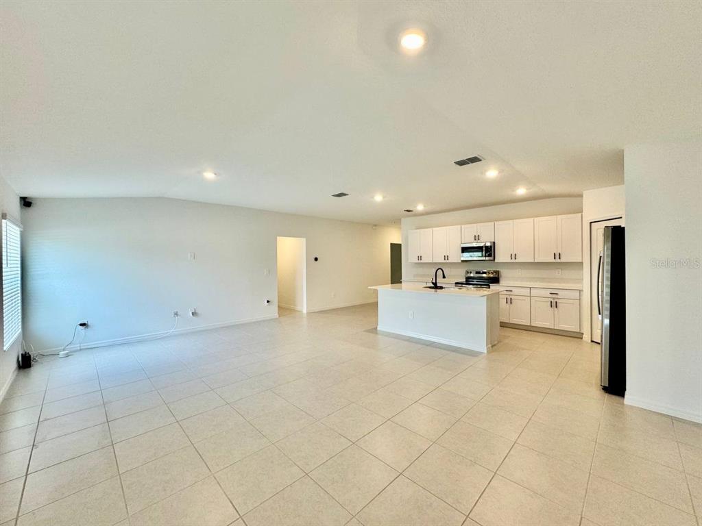 An open-concept kitchen with white cabinets and an island overlooks a spacious tiled living area — 10275 PURPLE LEAF COURT, RIVERVIEW, FL
