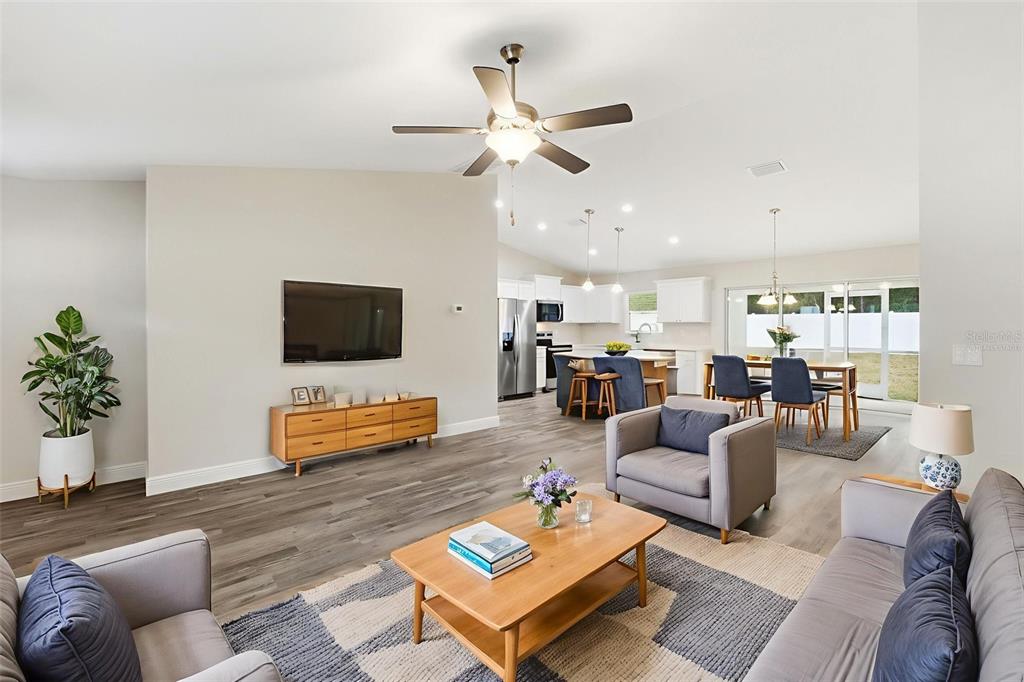 An open-concept living room and kitchen feature gray wood-look flooring and modern neutral decor — 9960 N SHERMAN DRIVE, CITRUS SPRINGS, FL