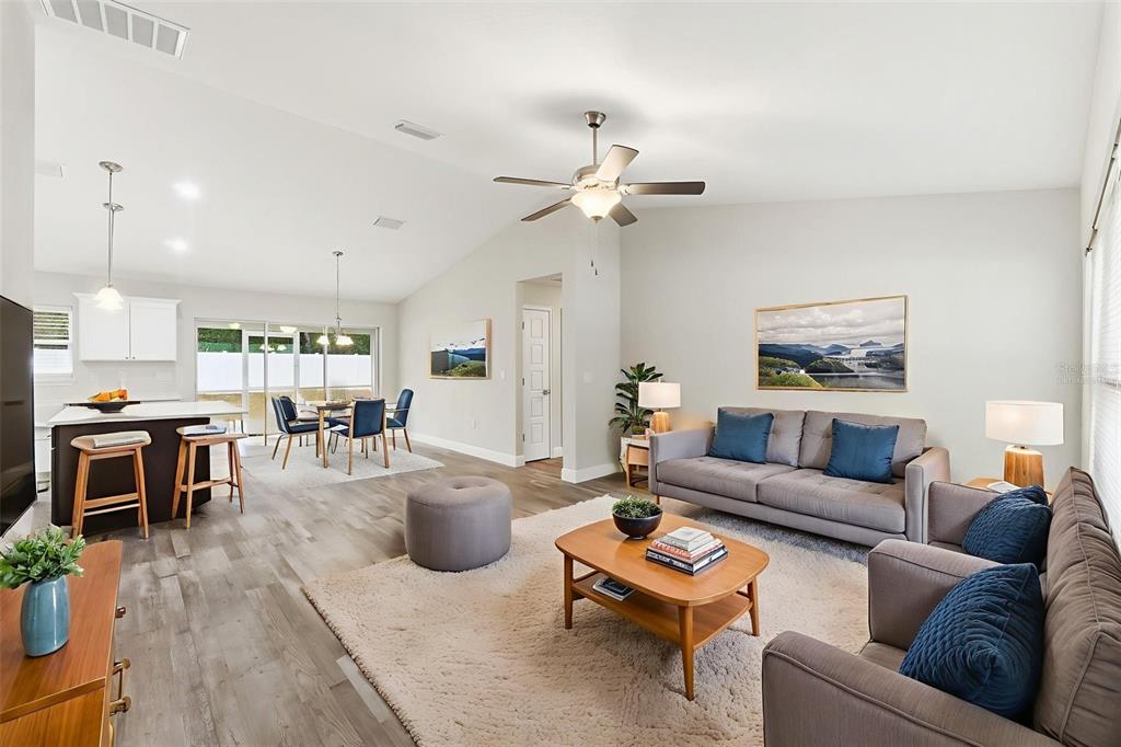 An open-concept living and dining area features light wood flooring, a vaulted ceiling, and furniture — 9960 N SHERMAN DRIVE, CITRUS SPRINGS, FL