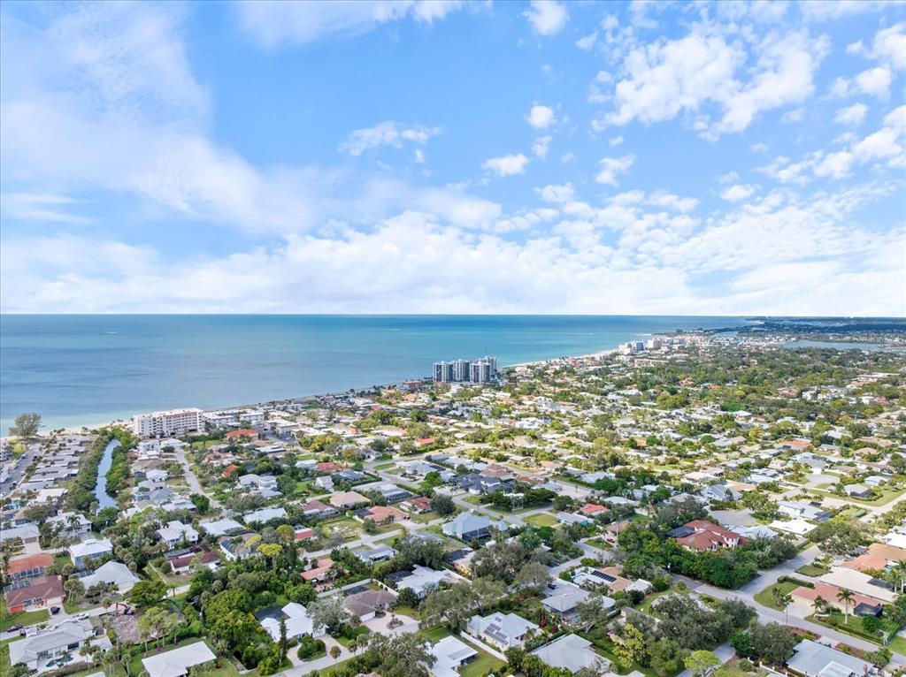 An aerial view shows a coastal residential neighborhood with houses, trees, and the ocean — 621 HIBISCUS DRIVE, VENICE, FL