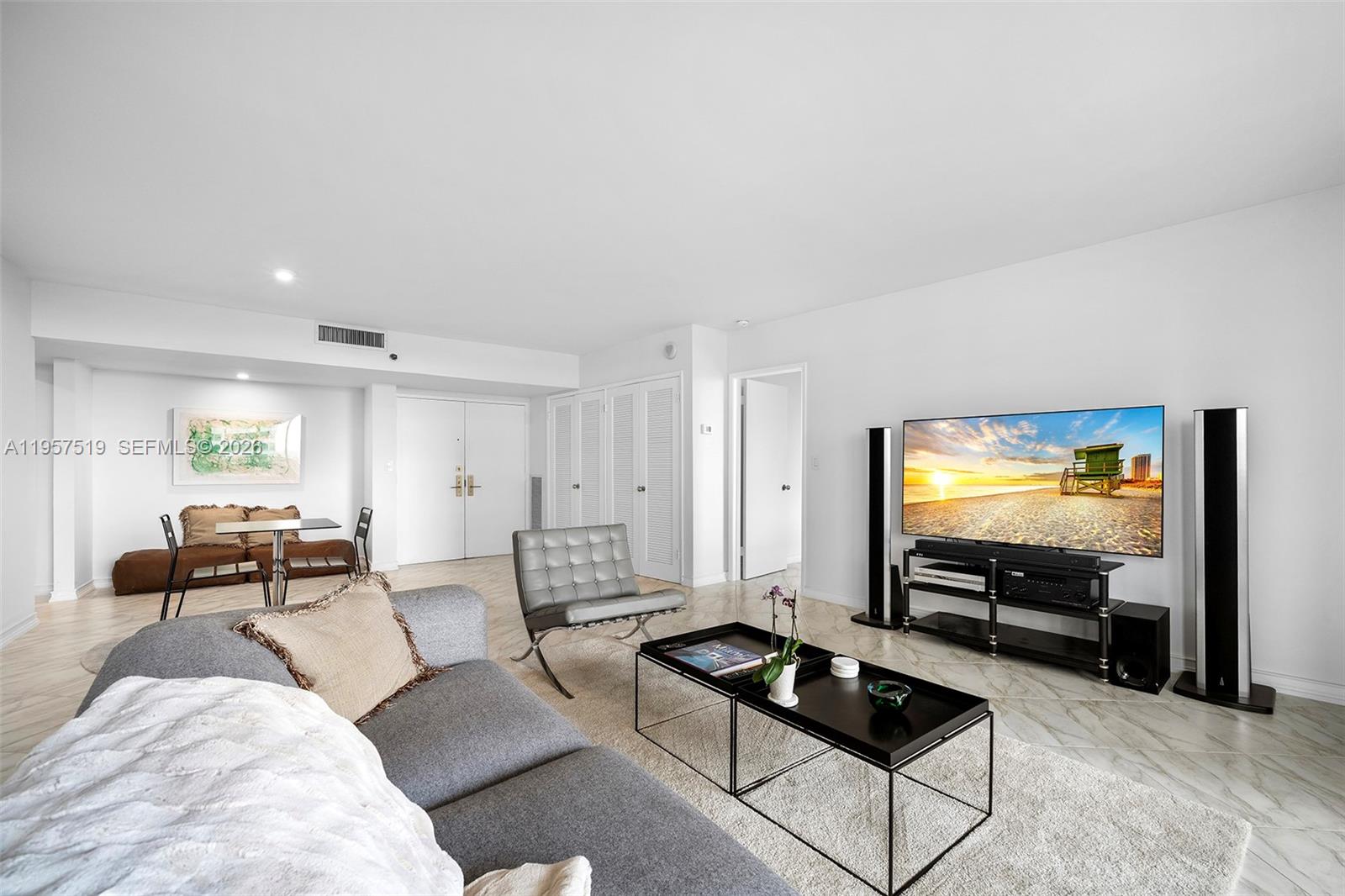 A living room features a grey sofa, a glass coffee table, and a television console — 9 Island Ave # 710, Miami Beach FL 33139, MIAMI BEACH, FL