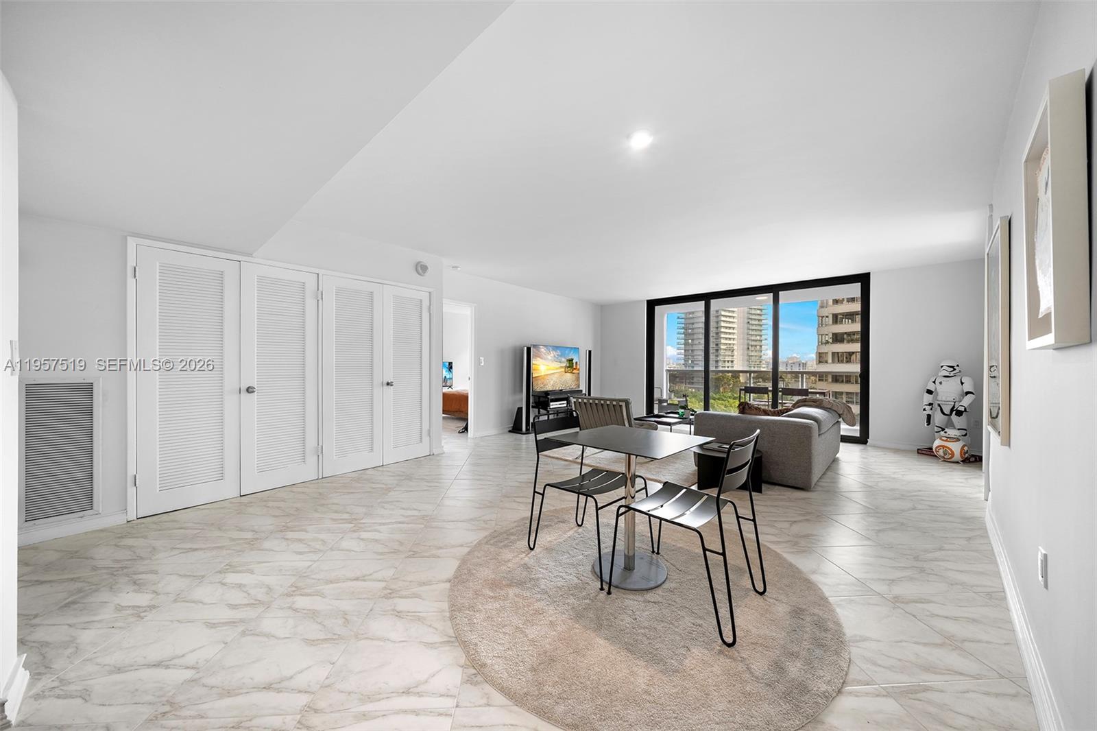 A bright living and dining area features white tile floors, a balcony, and a Stormtrooper figure — 9 Island Ave # 710, Miami Beach FL 33139, MIAMI BEACH, FL