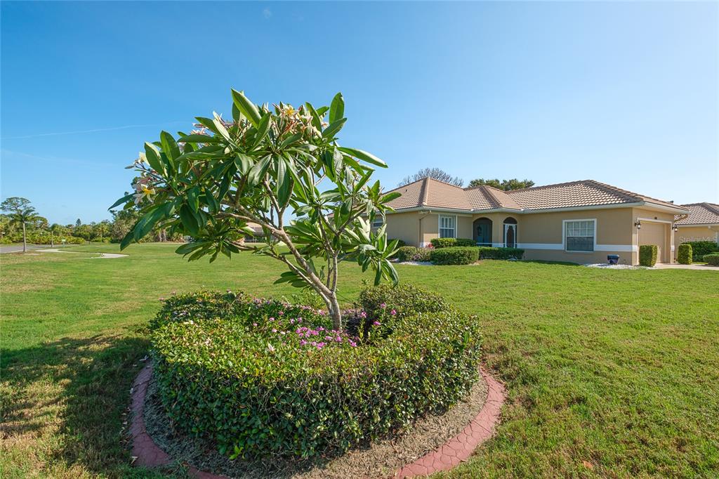 A single-story house with a tan exterior and a tiled roof sits on a lawn — 6700 GREENVIEW LANE, ENGLEWOOD, FL