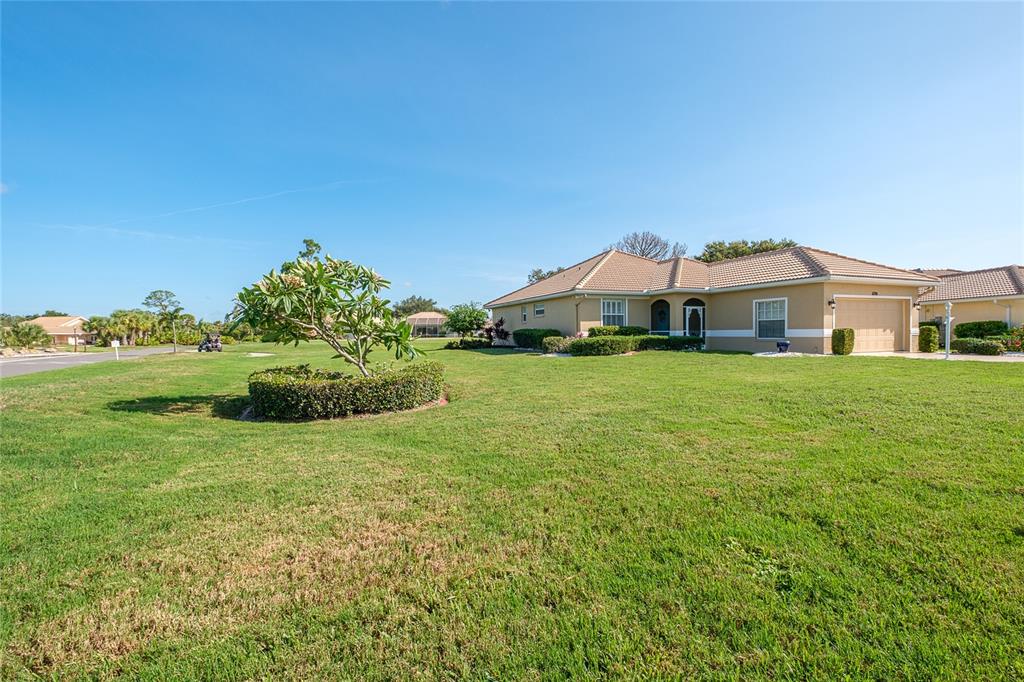 A single-story house with a tan exterior, tiled roof, and a large front lawn — 6700 GREENVIEW LANE, ENGLEWOOD, FL