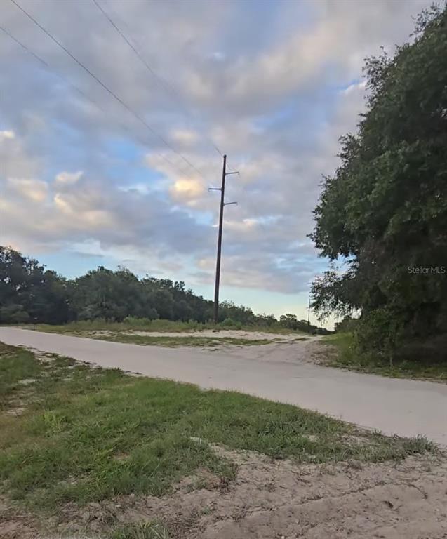 A paved road leads toward a utility pole in a grassy, wooded area — TBD S SAN ANGELO PARKWAY, DUNNELLON, FL