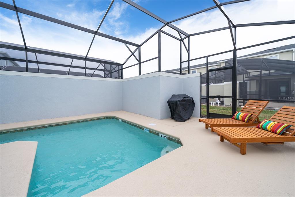 A screened-in patio features a small swimming pool, two lounge chairs, and a grill — 2990 PROTAGONIST STREET, KISSIMMEE, FL