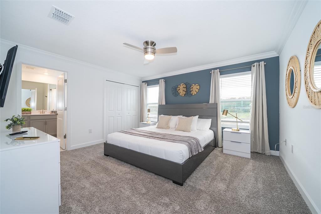 A bedroom features a gray bed, blue accent wall, and carpeted flooring — 2990 PROTAGONIST STREET, KISSIMMEE, FL