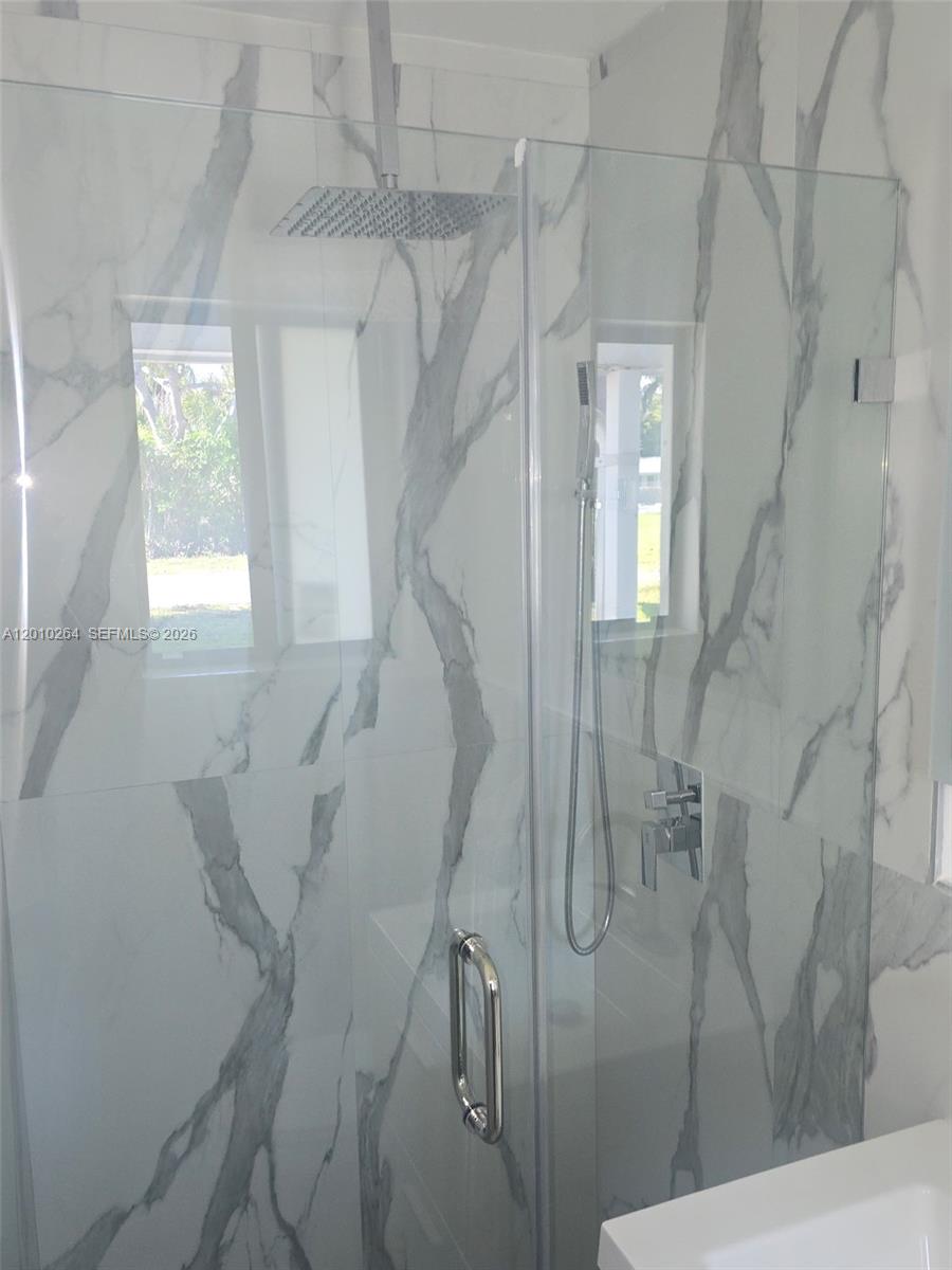 A glass-enclosed shower features white marble-look tile walls and a rainfall showerhead — 3300 SE 6th St # 2, Pompano Beach FL 33062, POMPANO BEACH, FL