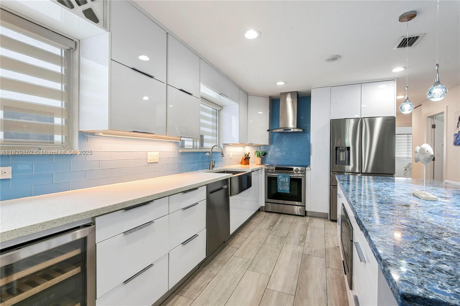 A modern kitchen features white cabinets, blue tile backsplash, stainless steel appliances, and a blue countertop — 325 Calusa St 96, Key Largo FL 33037, KEY LARGO, FL