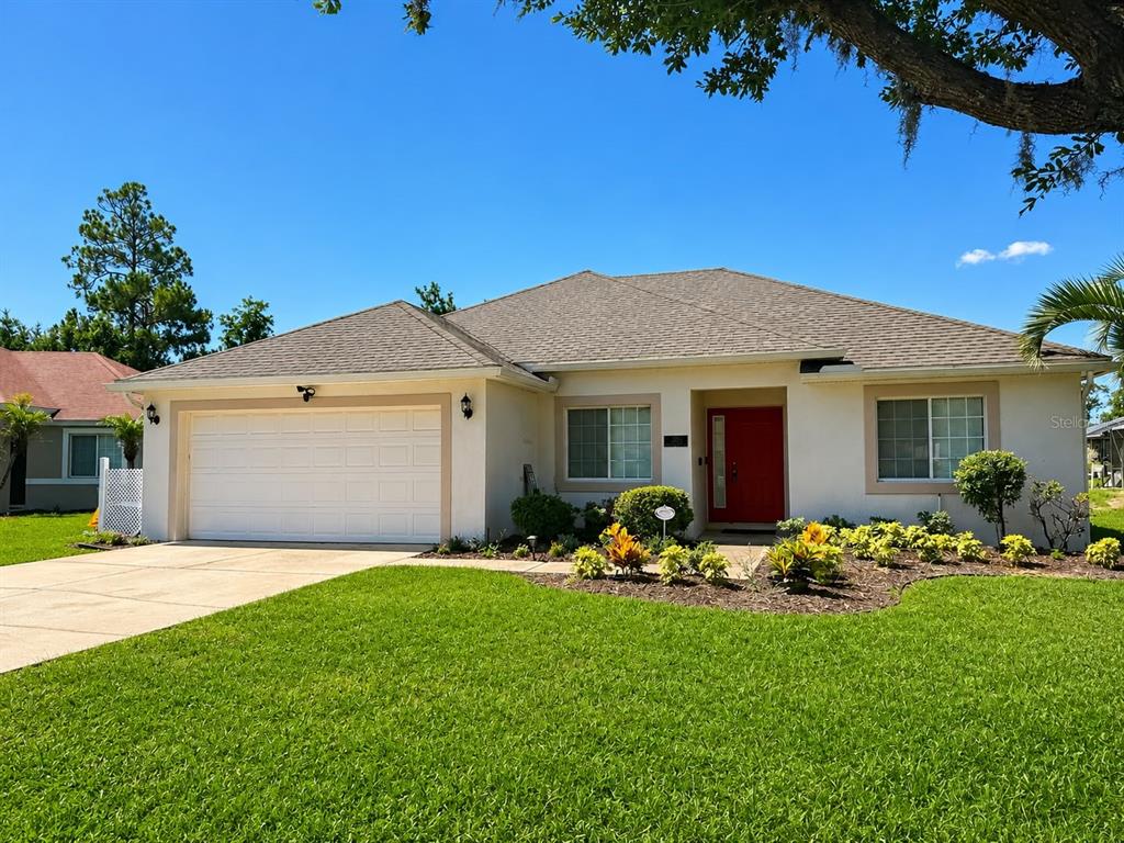 A single-story house with a white stucco exterior, red front door, and two-car garage — 320 PARADISE WOODS PLACE, DAVENPORT, FL