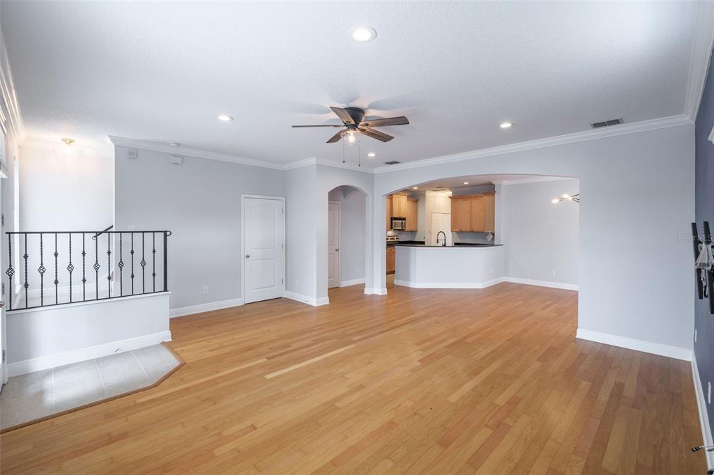 A spacious living room with hardwood floors, a ceiling fan, and an arched kitchen entrance — 1807 HAMMERLIN AVENUE UNIT G, WINTER PARK, FL