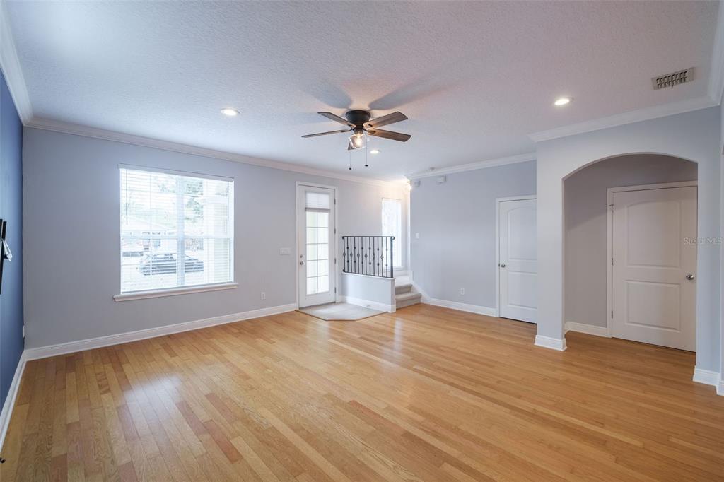 A living room with light blue walls, hardwood floors, a ceiling fan, and a door — 1807 HAMMERLIN AVENUE UNIT G, WINTER PARK, FL