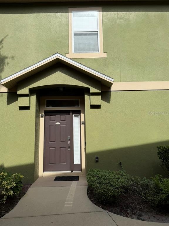 A green stucco building exterior features a brown front door with a side window — 3310 PINE OAK TRAIL, SANFORD, FL