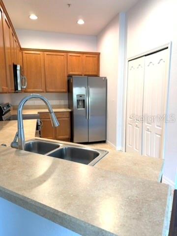 A kitchen features wood cabinets, a stainless steel refrigerator, and a double-basin sink — 3310 PINE OAK TRAIL, SANFORD, FL