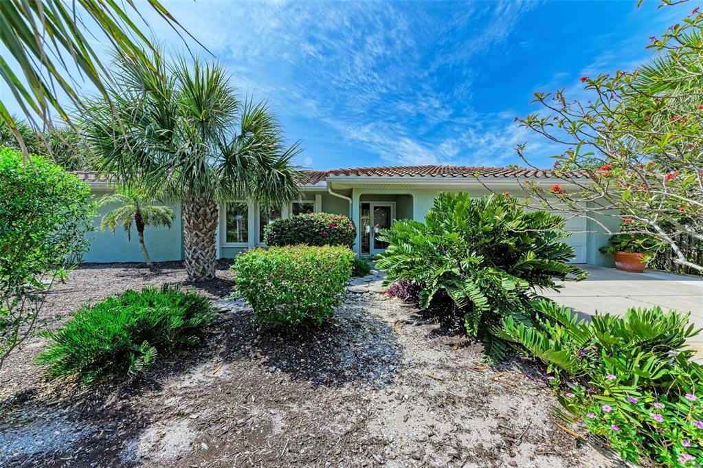 A single-story house with a tile roof, light-colored exterior, and lush landscaping in the front — 8320 MANASOTA KEY ROAD, ENGLEWOOD, FL