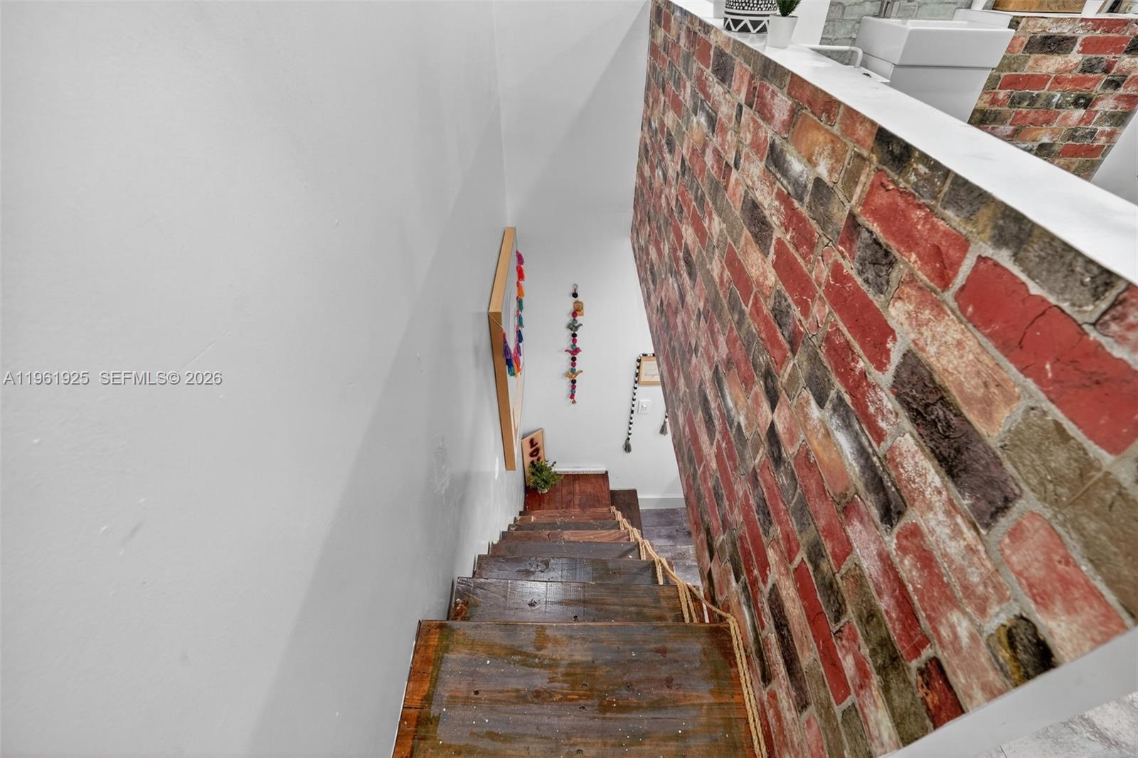 A wooden staircase descends beside a brick wall in an interior space — 8750 W Flagler St # 2, Miami FL 33174, MIAMI, FL
