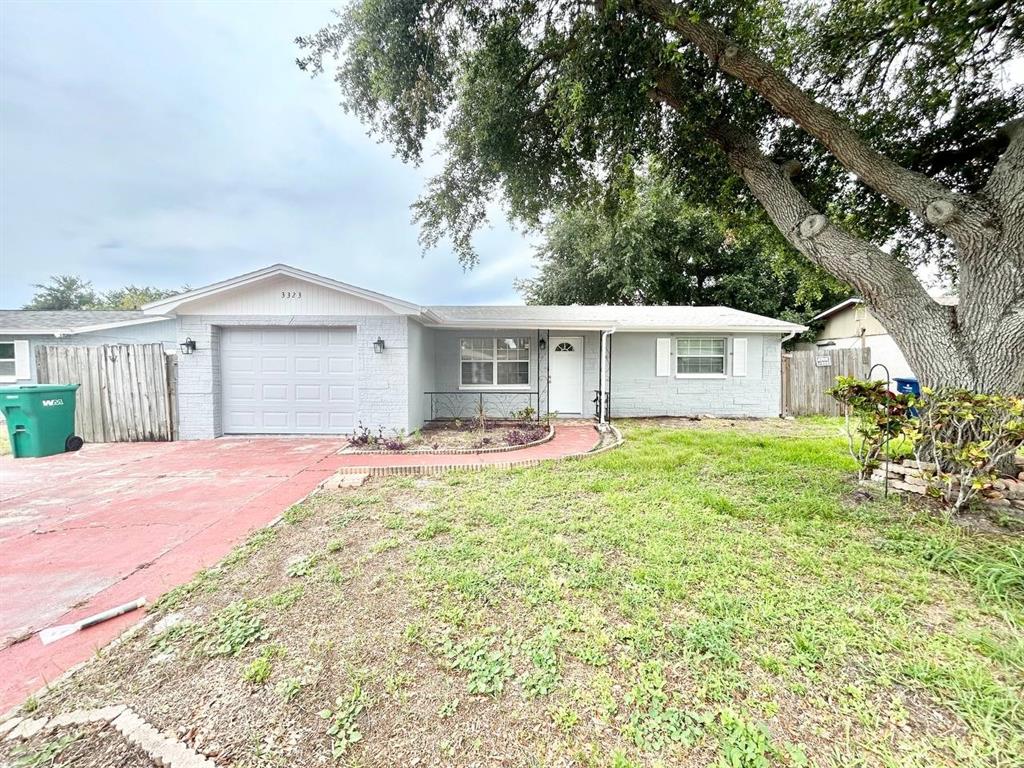 A single-story house with a light gray exterior, a one-car garage, and a large tree — 3323 FAIRMOUNT DRIVE, HOLIDAY, FL
