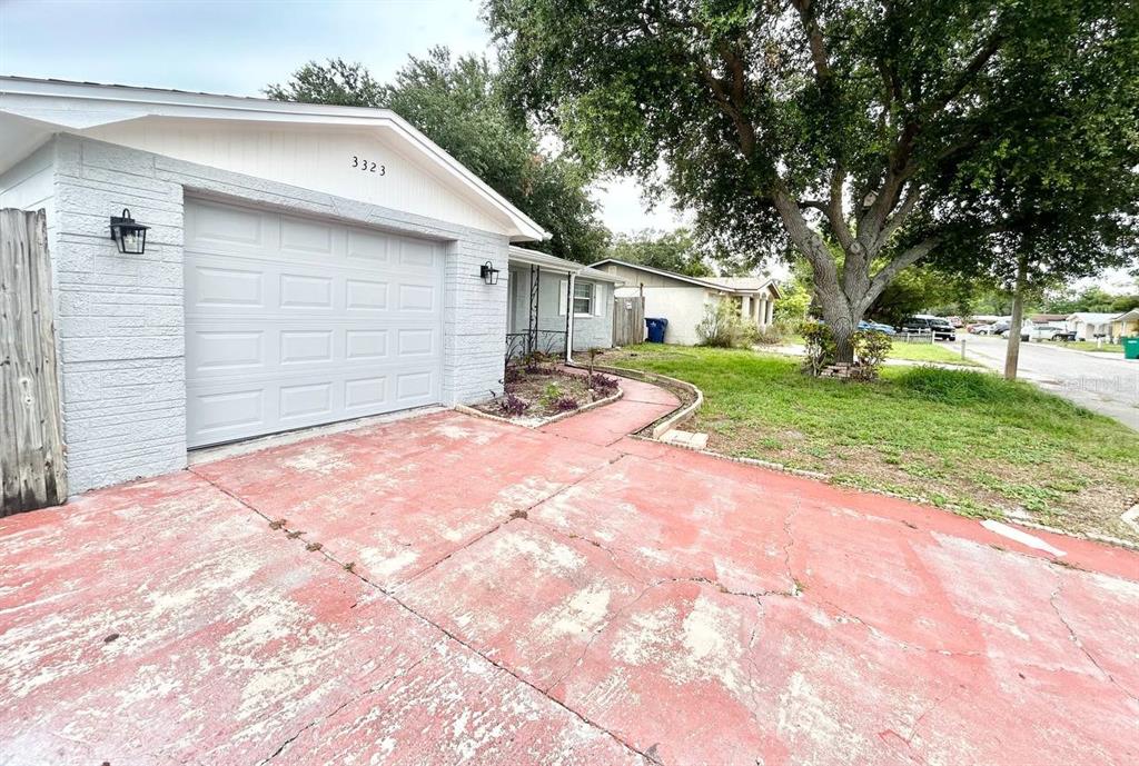 A single-story house with a white garage door, light gray siding, and a red driveway — 3323 FAIRMOUNT DRIVE, HOLIDAY, FL